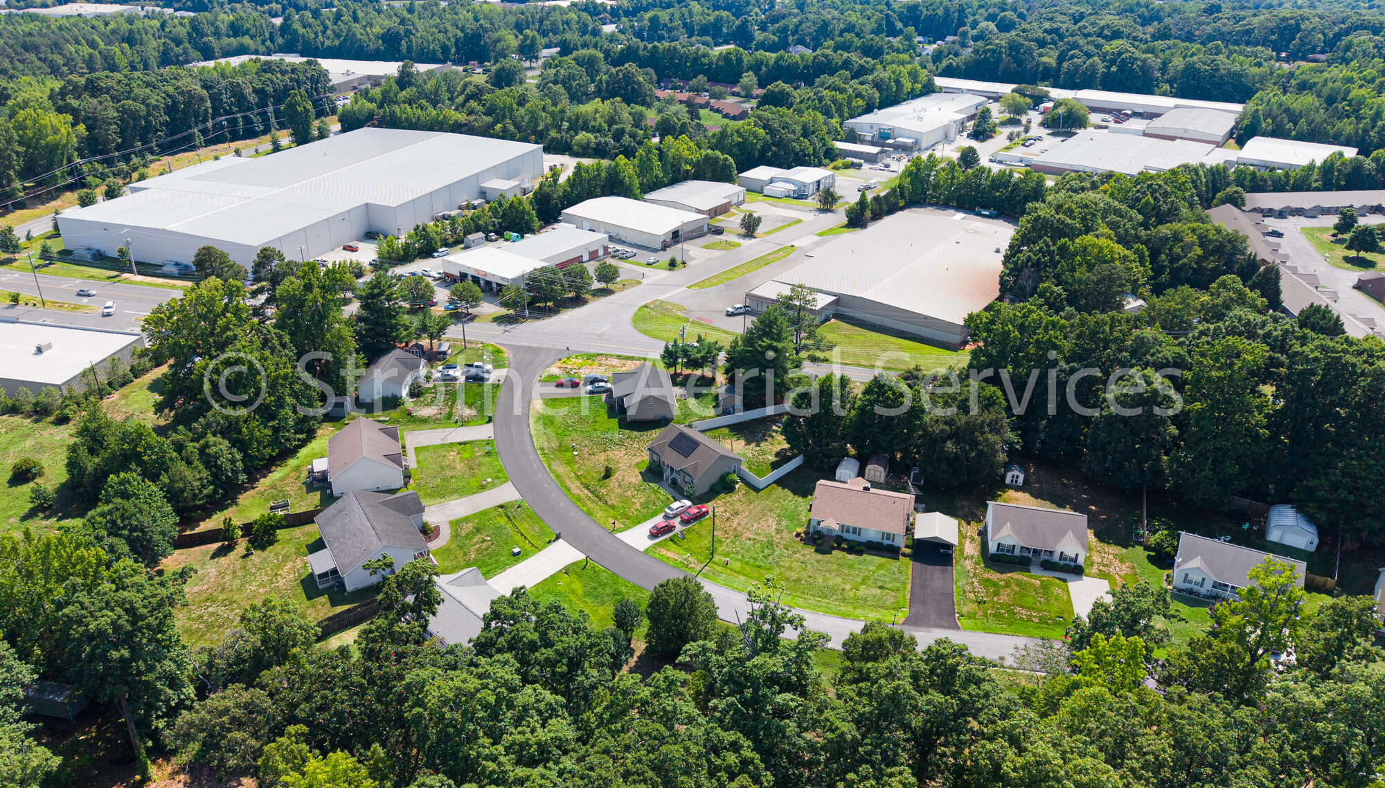 Aerial view of homes alongside a commercial and industrial corridor